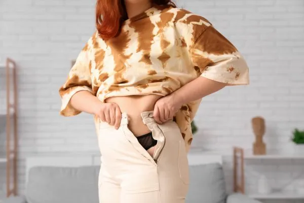 Image of woman trying to do her trousers up after pregnancy weight gain Bellshill